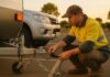 Our Top 5 Caravan Safety Tips Driver checking caravan hitch, safety chains and trailer lights before departure.