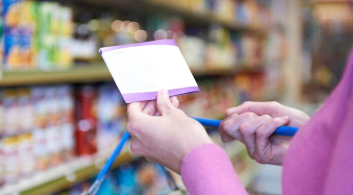 Product Bundles for Ultimate Savings Close-up of a person holding a shopping list while pushing a cart in a grocery store aisle, focusing on budgeting and planned shopping bundles