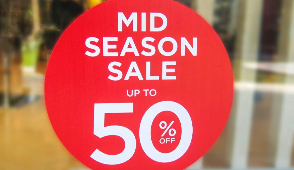 Mid-season sale sign with bold white text on a red circular background, advertising up to 50% off