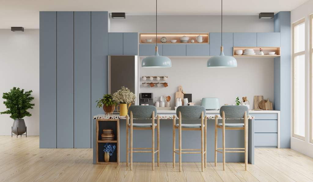 Modern kitchen with pastel blue cabinets, a white countertop island with three barstools, pendant lights, and decorative elements such as plants, wooden cutting boards, and open shelving with dishes furniture