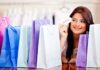 Special Offers You Can Not Resist Smiling woman holding a 'SALE' card, surrounded by colorful shopping bags, representing a successful shopping spree and discounts bundles