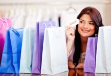 Special Offers You Can Not Resist Smiling woman holding a 'SALE' card, surrounded by colorful shopping bags, representing a successful shopping spree and discounts bundles