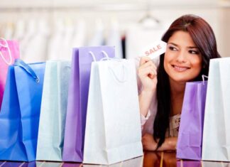 Special Offers You Can Not Resist Smiling woman holding a 'SALE' card, surrounded by colorful shopping bags, representing a successful shopping spree and discounts bundles