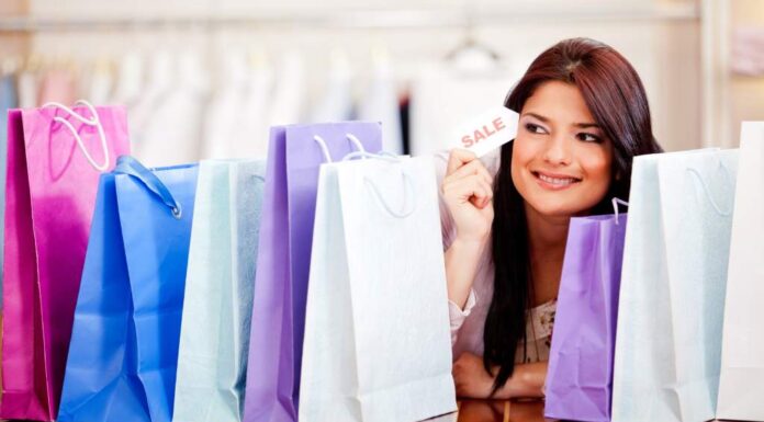 Special Offers You Can Not Resist Smiling woman holding a 'SALE' card, surrounded by colorful shopping bags, representing a successful shopping spree and discounts bundles